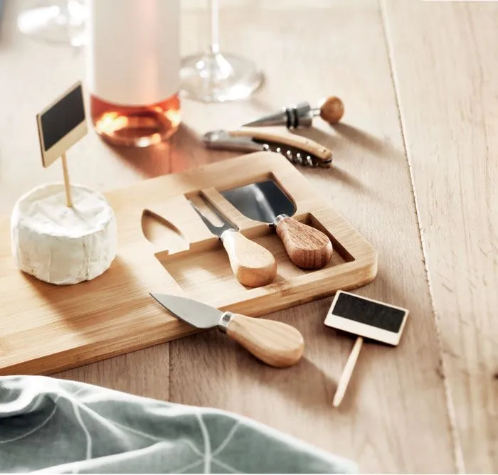 Bamboe kaasplank met messen en wijn-accessoires op een gedekte tafel