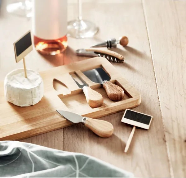 Bamboe kaasplank met messen en wijn-accessoires op een gedekte tafel