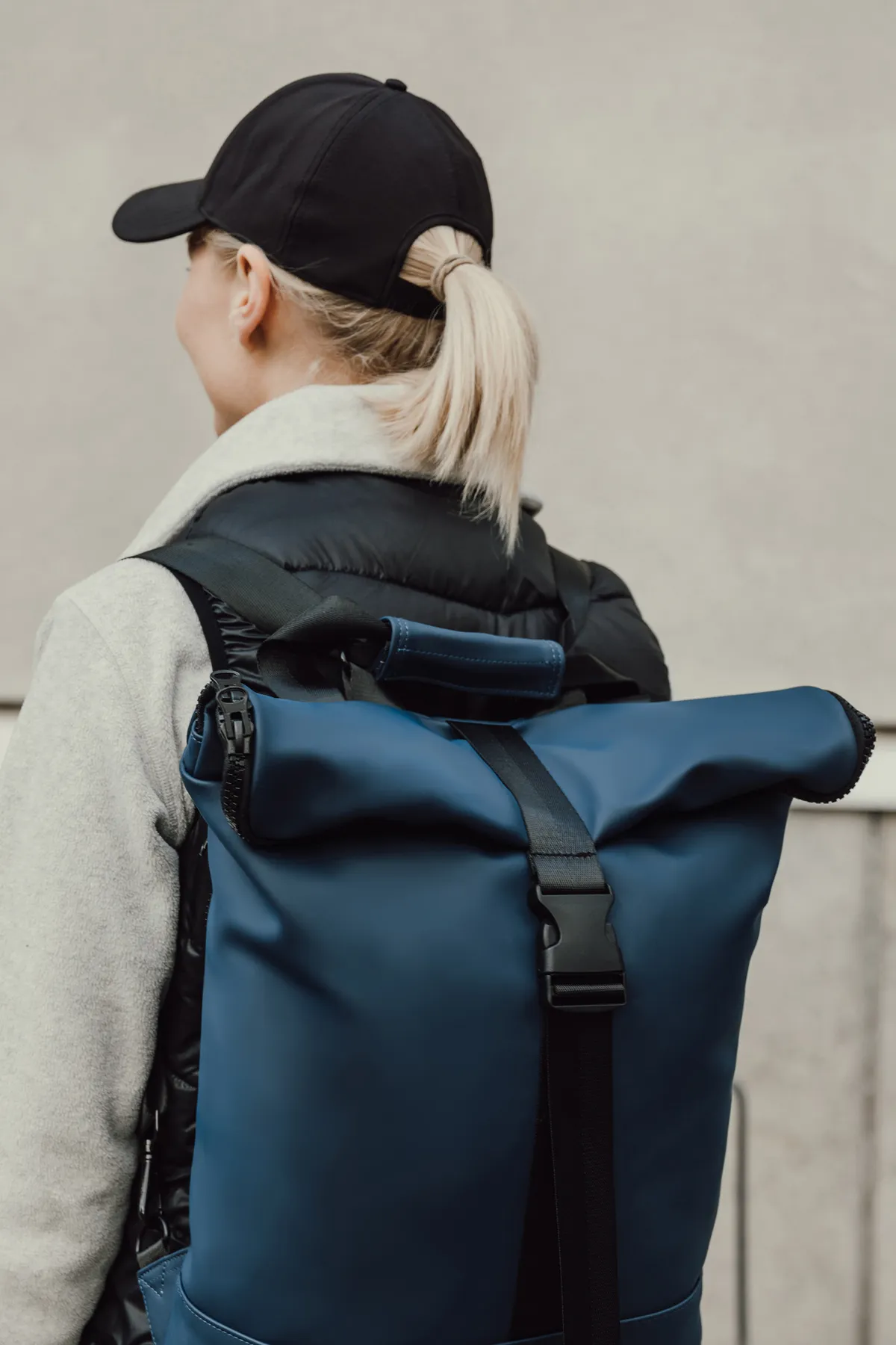 Blauwe rolltop rugzak met zwarte gespen en schouderbanden