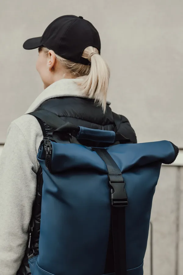 Blauwe rolltop rugzak met zwarte gespen en schouderbanden